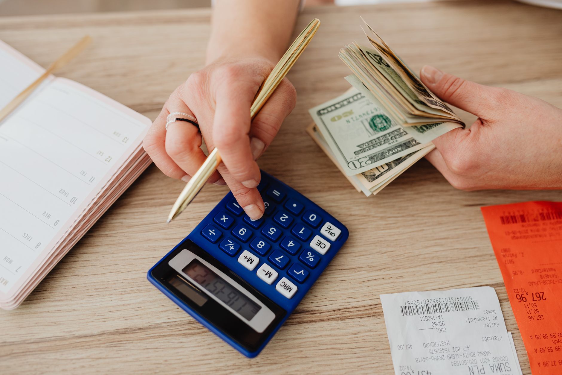 Hands using cash and a calculator for a household budget