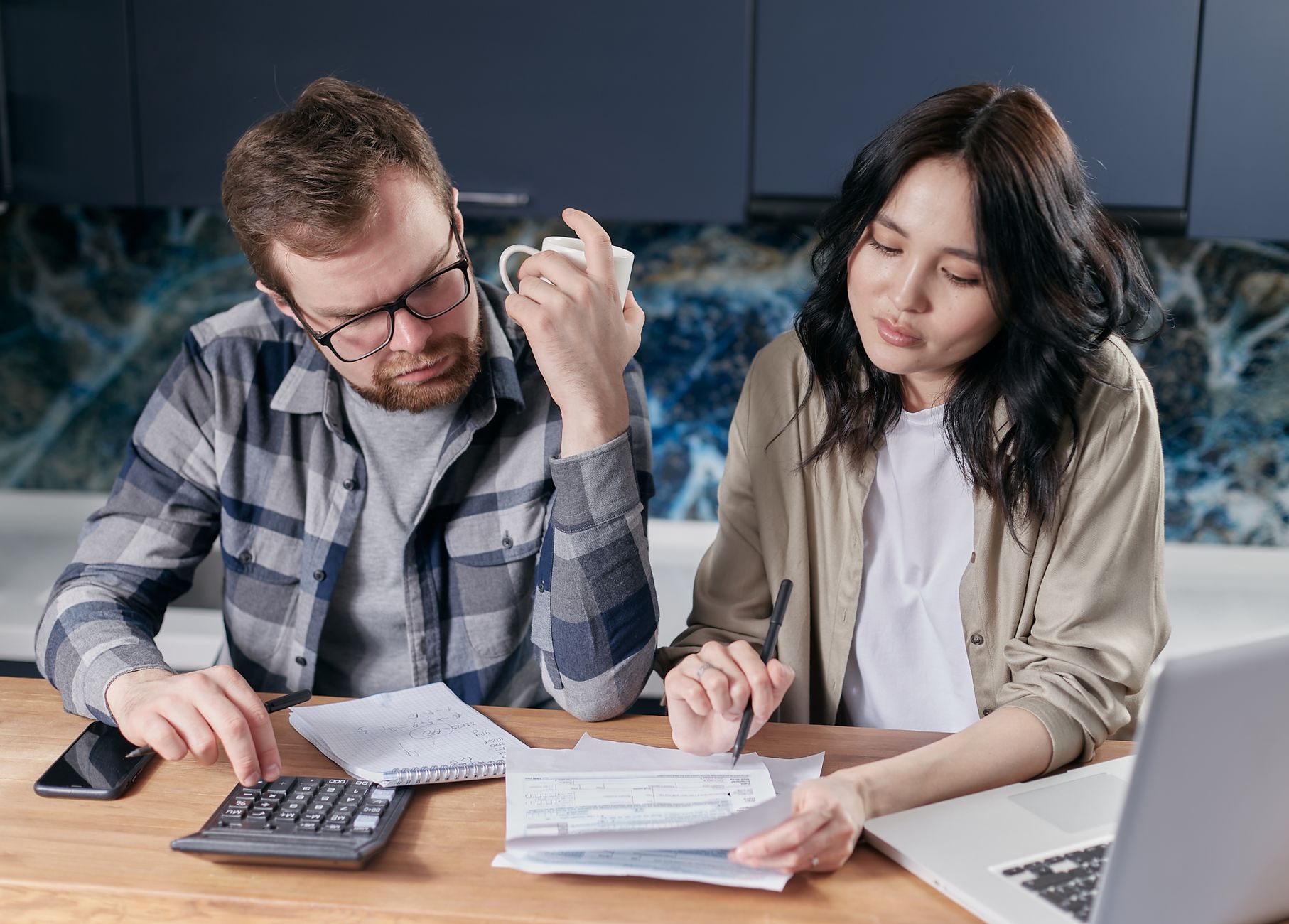 Couple reviewing household bills with a laptop and calculator