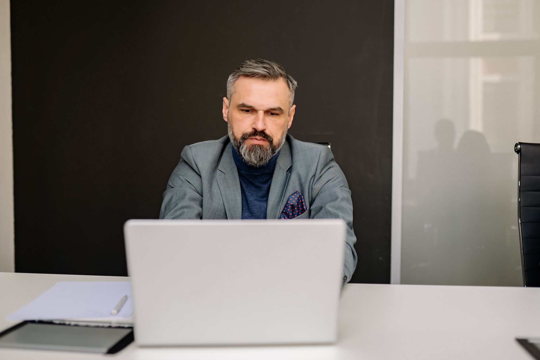Middle-aged professional man concentrating on his work using a laptop in an office environment.